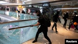 资料照:香港一名抗议者正在打碎九龙一家商场的玻璃围栏。(2019年11月12日)