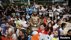 2015年7月22日,韩国首尔的抗议者们围坐在一尊“慰安妇”塑像边,要求日本政府道歉并赔偿。