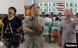 在武汉的证券交易市场,股民们看着电脑屏幕上的股市行情(2015年7月3日)