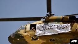 塔利班在阿富汗坎大哈举行的庆祝仪式上展示挂有塔利班旗帜的直升飞机(2021年9月1日)