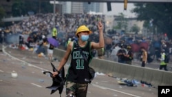 一名抗议香港逃犯条例修订的香港示威者向与抗议者发生冲突的防暴警察做手势。(2019年6月12日)