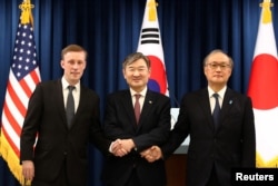 2023年12月9日,韩国国家安全顾问赵太庸(中)与美国国家安全顾问杰克·沙利文(Jake Sullivan)和日本国家安全保障秘书处秘书长秋叶刚男(Takeo Akiba)在韩国首尔总统府举行的联合记者招待会后握手。