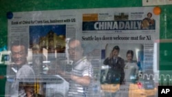 北京民众走过一处陈列着《中国日报》的报摊 (美联社 2015年9月23日)