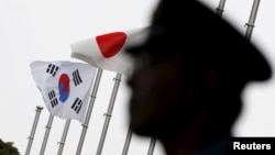 一名日本警察站在东京一家飘扬着日韩国旗、正在举行日韩关系50周年庆祝仪式的酒店前执勤。(2015年6月22日)