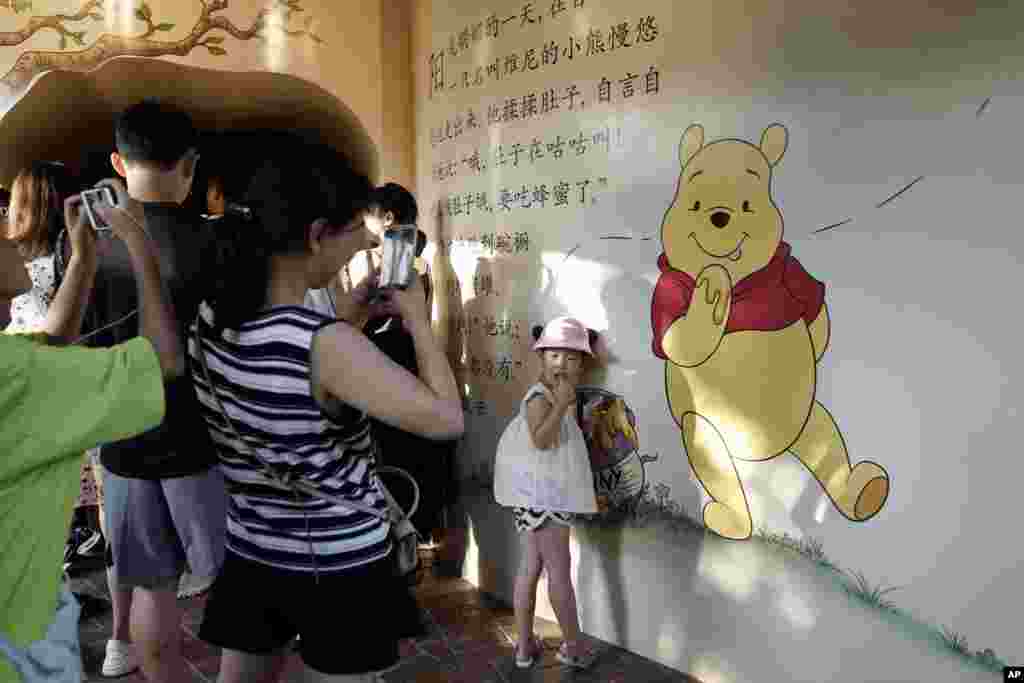 2018年8月8日,在上海的一幅描绘小熊维尼的壁画前面,一名儿童摆姿势拍照。改编自迪士尼经典动画《小熊维尼》的真人版电影《挚友维尼》在中国没拿到放映许可,从而被拒于全球第二大电影市场之外。