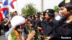 Người biểu tình chống chính phủ tặng hoa hồng đỏ cho cảnh sát tại Bangkok, ngày 3/12/2013. Chính phủ Thái Lan ra lệnh cho cảnh sát dỡ bỏ rào cản và cho phép người biểu tình vào các tòa nhà chính phủ.