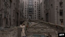 Жінка фотографує наслідки ракетної атаки на передріздвяний Київ, 20 грудня 2024р. Roman PILIPEY/AFP