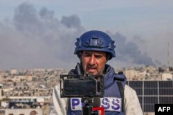 (FILES) Seorang jurnalis Palestina menggunakan ponsel untuk menyiarkan langsung perkembangan berita dari Rafah di Jalur Gaza selatan, 27 Desember 2023. (SAID KHATIB / AFP)