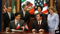 墨西哥负责北美事务的前外交部副部长古铁雷斯(前左)和美国职业安全和健康管理局前局长亨肖(前右)签署一项工作场所安全协议(2004年7月21日,资料图片)