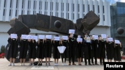 香港中文大学毕业生举起被中国拘押的12名港人的姓名牌子以示抗议。(2020年11月19日)