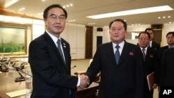 韩国首席代表、统一部长赵明均(Cho Myoung-gyon)和朝鲜首席代表、和平统一委员会主席李善权(中)在板门店非军事区举行会谈后握手(2018年1月9日)