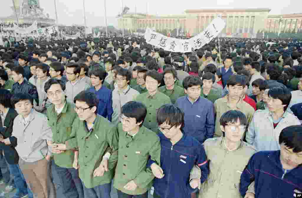 1989年4月22日,在北京天安门广场黎明时分,中国学生手挽手。他们在广场过夜,以便参加胡耀邦追悼会。
