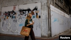 一名女子走过香港尖沙咀街头倒闭的商店。(2024年4月29日)