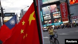 一名台湾妇女骑车从台北街头举行的台湾亲中国组织呼吁和平统一的一个集会前驶过。（2016年5月14日）