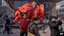 资料图 - 2021年中国农历新年期间,人们佩戴口罩防止传播新冠病毒。