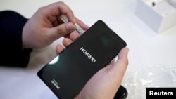 资料照:北京一名销售员为顾客启动华为的P30手机。华为手机被发现把上面原有的时区设定从“台湾”变成了“台湾(中国)”。