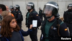 2017年10月1日,在西班牙圣圣胡利娅-德洛里亚市一个被禁独立公投的投票站外,一名女子向西班牙民事卫队人员展示选票。