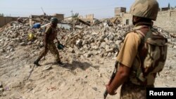 Binh sĩ Pakistan đứng gần đống đổ nát của một ngôi nhà bị phá hủy trong một cuộc phản công chống Taliban.