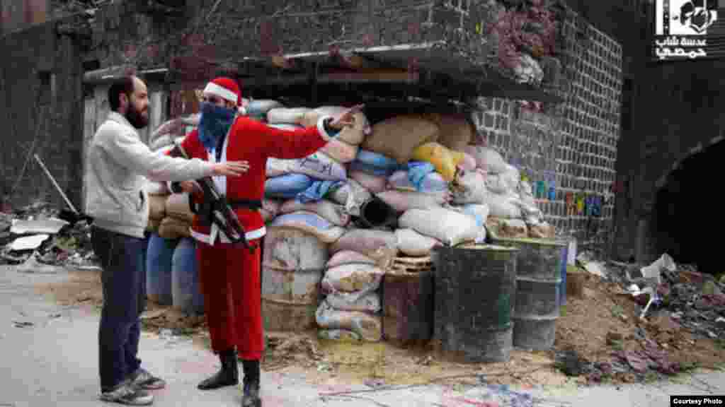 Một binh sĩ của phe nổi dậy trong trang phục ông già Noel chỉ đường cho cư dân tại thành phố cổ ở Homs, ngày 1/1/2013.