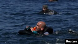 叙利亚难民抱着一个婴儿,向达莱斯沃斯岛游去(2015年9月13日)。