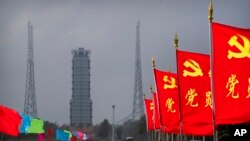 2020年11月23日，中国共产党的旗帜在中国海南省文昌航天发射场的发射台附近飘扬，技术人员正在为嫦娥五号探测器的发射工作做准备。