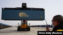 资料照:中国内蒙古自治区乌兰察布市货运站的工人正在从俄罗斯鄂木斯克发来的中欧班列上装载集装箱。(2020年2月20日)