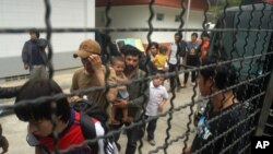 逃到泰国的维吾尔穆斯林在一辆警车旁站队(资料照片2014年3月15日)