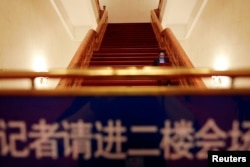 在全国人大会议投票表决通过修宪案后，一名记者坐在北京人大会堂的台阶上工作。（2018年3月11日）