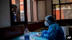 在印度首都新德里,一位医护人员正在记录新冠患者的名字。