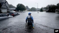 北卡罗来纳州城市搜索和救援队的一名成员2018年9月16日在费耶特维尔的倾盆大雨中,在一个被洪水淹没的街区寻找没有撤离的居民。