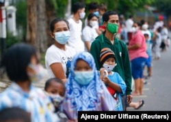 Orang-orang yang mengenakan masker pelindung antre untuk menerima makan gratis berbuka puasa selama bulan suci Ramadhan di tengah pandemi COVID-19 di Jakarta, 15 April 2021. (Foto: REUTERS/Ajeng Dinar Ulfiana)