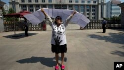 2013年8月21日,一名女子在济南中级人民法院前抗议。对薄熙来的审判引来一些抗议和上访者,有人挺薄,也有人借机诉说自己的冤情。