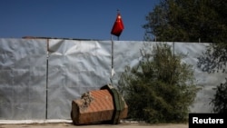 新疆乌鲁木齐外昌吉市一所清真寺被拆掉的尖塔残骸的一部分与中国国旗。 (2021年5月6日)