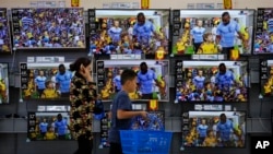 一名妇女和男孩走过北京商场的电视销售区。(2018年7月11日)