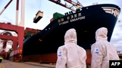 身穿防护服的中国海关人员在山东省青岛港检查一艘货轮。（2020年11月16日）