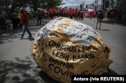 Tulisan "omnibus law lebih berbahaya dari COVID" tampak di tengah demo buruh memprotes Undang-Undang Cipta Kerja, di Bandung, Jawa Barat, Selasa, 6 Oktober 2020. (Foto: Antara via Reuters)