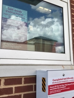 新冠病毒得来速检测站。医护人员在玻璃窗后用对讲机指示,右下为检测小包搜集箱。 (美国之音黄耀毅拍摄)