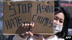 一名示威者在洛杉矶中国城附近手举标语牌参加反对针对亚裔暴力犯罪的活动。(2021年2月20日)