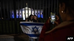 白宫2023年10月9日晚亮出以色列国旗的灯光，支持者们在大门前留影。（法新社）