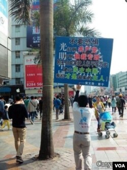 黄文勋举着一块足有一平方米大的标语牌走上了深圳人流熙攘的大街(2013年3月10日)