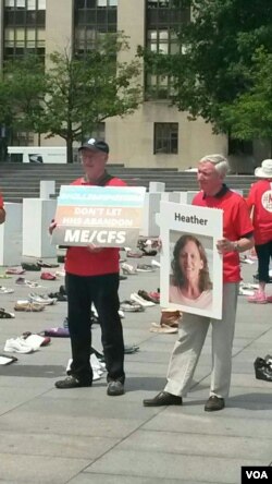 抗议者手握标语牌和患病家人的照片。(美国之音乔栈拍摄)