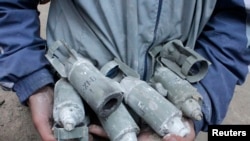 Một thiếu niên cầm trên tay những quả bom nhỏ chưa nổ được bắn ra từ những quả bom chùm do máy bay của quân đội chính phủ Syria thả xuống quận al-Meyasar, thuộc Aleppo, ngày 21/2/2013.