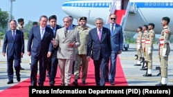 巴基斯坦总理谢里夫(中)在机场欢迎中国总理李强抵达伊斯兰堡。(2024年10月14日)