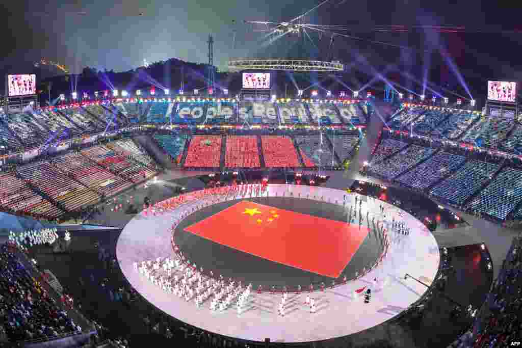 2018年平昌冬奥会开幕式上,中国运动员入场时,平昌体育场显示中国国旗(2018年2月9日)。 开幕式上体育爱好者冒着严寒观看焰火、壮丽灯光秀,以及运动员队伍步入奥运体育场。 本届冬奥会将持续到2月25日结束。