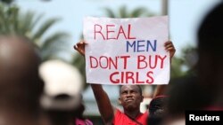 Một người đàn ông cầm biểu ngữ phản đối vụ bắt cóc và yêu cầu thả các nữ sinh.