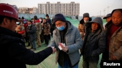 北京一处建筑工地里一个工头给打工工人发工资过年。(2021年2月6日)