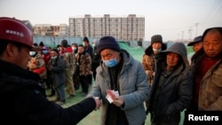 资料照:北京一处建筑工地里一个工头给工人发工资。(2021年2月6日)