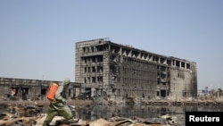 一名身穿防护服的中国防化兵在天津爆炸现场向废墟喷洒液体。(2015年8月21日)