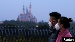 戴着口罩的上海市民从春节期间关闭的迪斯尼乐园旁走过。(2020年1月24日)
