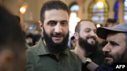 Para pendukung menyambut pemimpin kelompok Islamis Hayat Tahrir al-Sham (HTS) Suriah yang memimpin serangan merebut Damaskus dari kendali pemerintah, Abu Mohammed al-Jolani (tengah), 8 Desember 2024. (Foto: AFP)